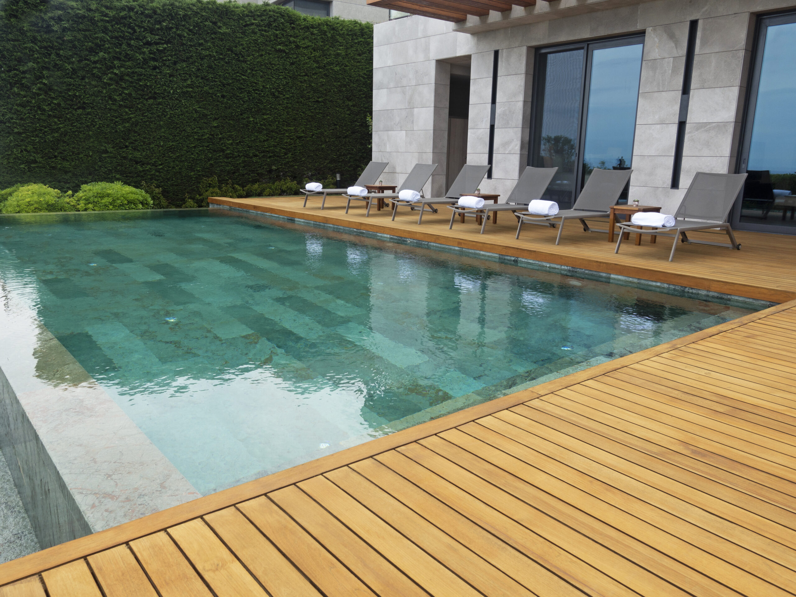 Deck chairs on Wooden plank floor against swimming pool Deck chairs on Wooden plank floor against swimming pool